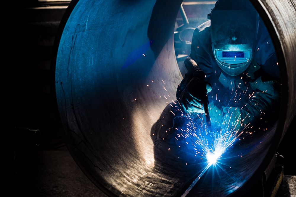 pipe fabricating welder working on inside of heavy industrial pipe